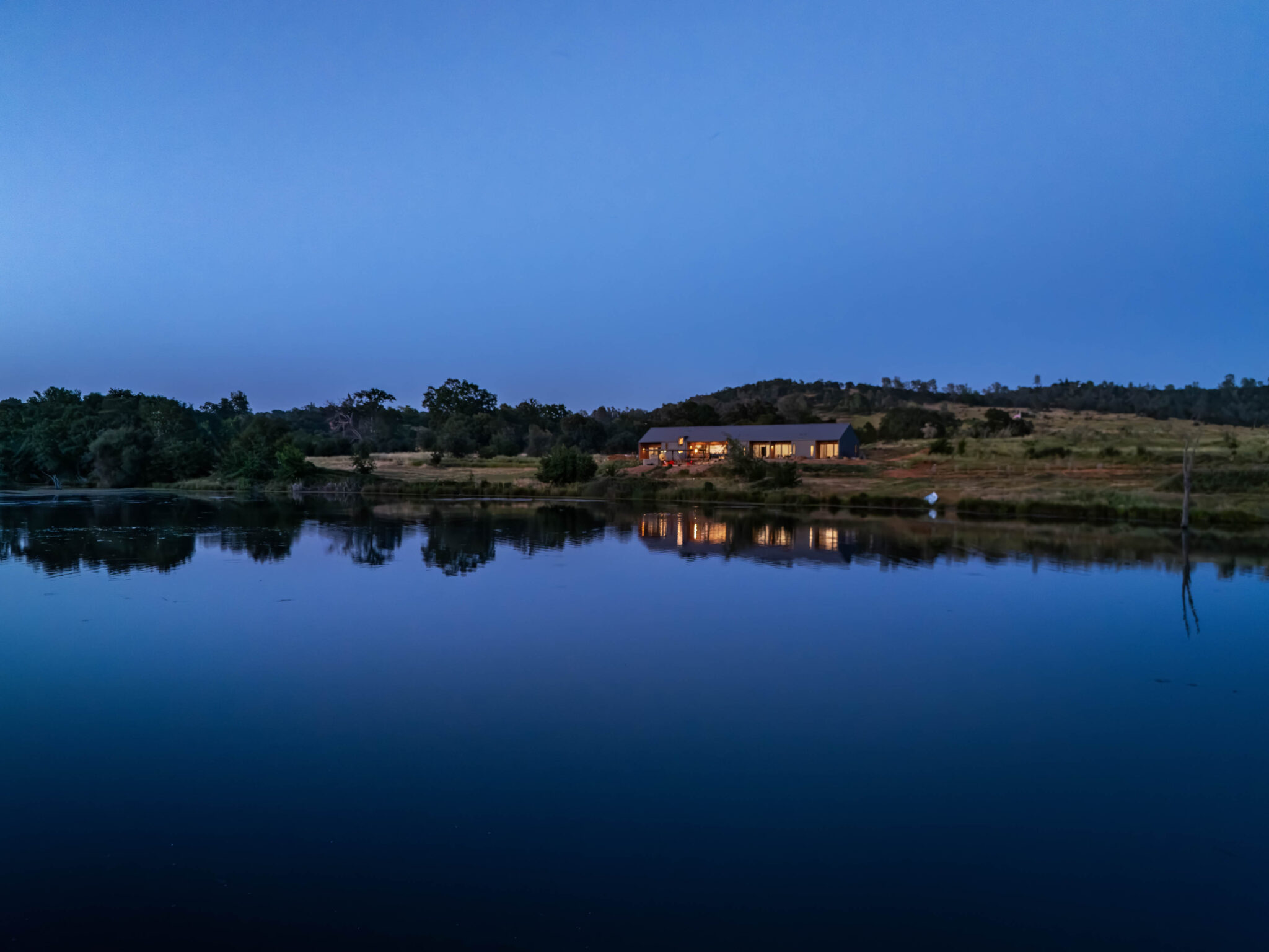 JNT custom home exterior evening view over the pond